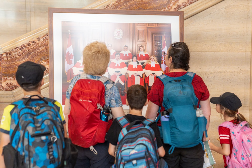 Un groupe d’adultes et d’enfants qui portent des sacs à dos regardent une photo des juges