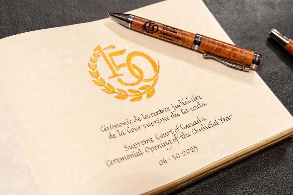 Le livre commémoratif qu’ont signé les participants à la cérémonie, qui est ouvert à la première page. La page porte le logo du 150e anniversaire de la Cour en or, ainsi que le nom et la date de l’événement.