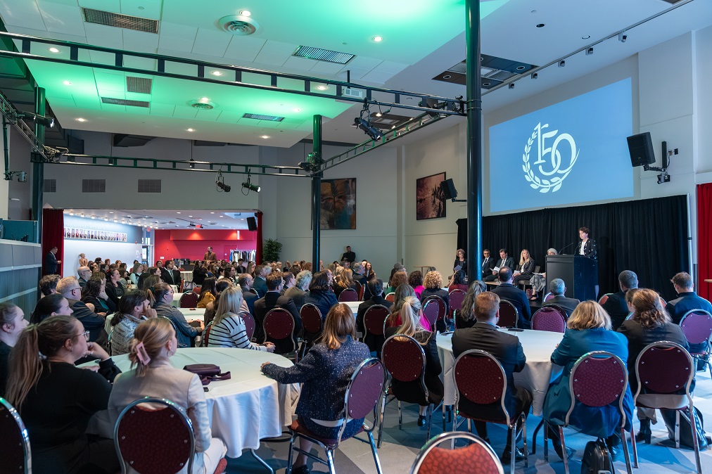 The judges sit on stage with other guests while Marie-Pierre Robert addresses the audience at a reception.