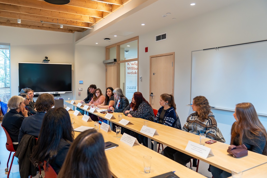 The judges discuss with Indigenous students around a table.