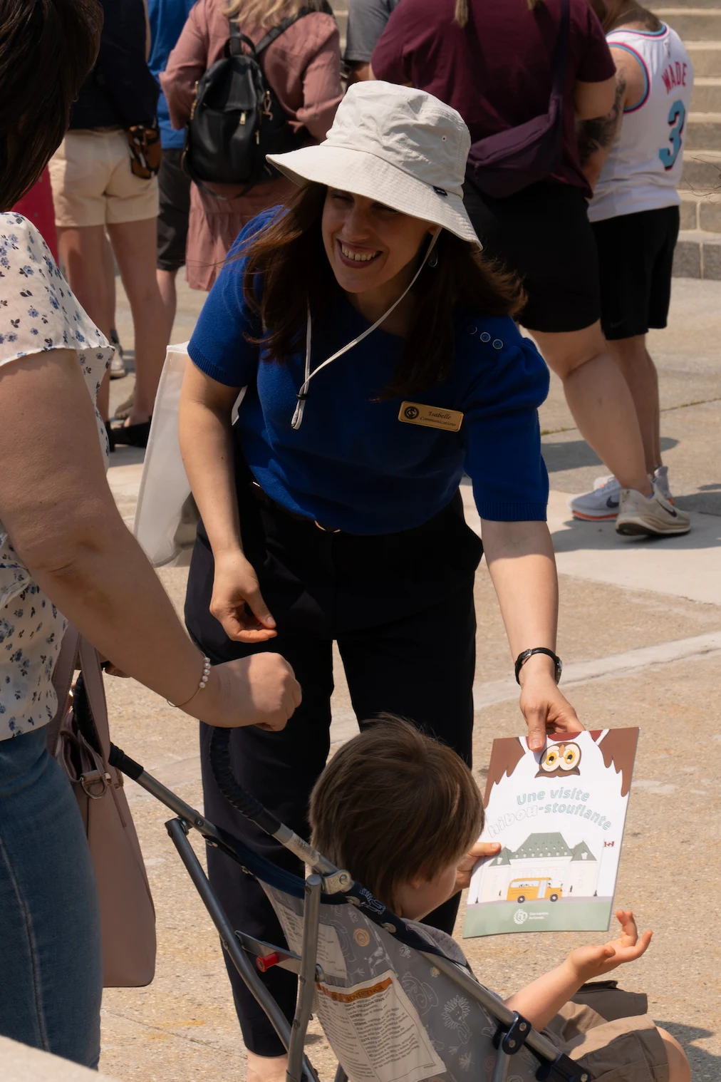 A member of the Court staff is distributing the children’s book to a child in a stroller