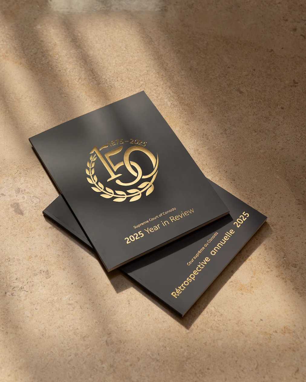 The English version of the 2025 Year in Review with the French version underneath. The cover is dark blue with the Court’s anniversary logo in gold.