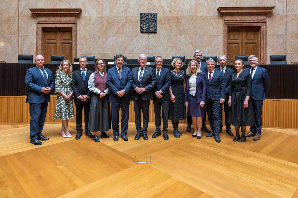 Group photo of the Chief Justice, the judges and representatives from the Constitutional Court of the Czech Republic, in a courtroom.