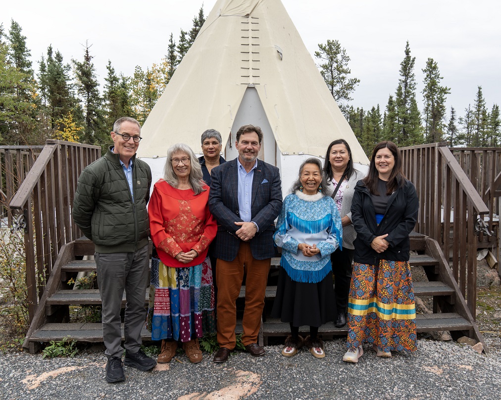 A group photo of Chief Justice Wagner, Justice Kasirer, Justice O’Bonsawin, Justice Smallwood and Justice Khullar with Elders from the Arctic Indigenous Wellness Foundation, in front of a tent.
